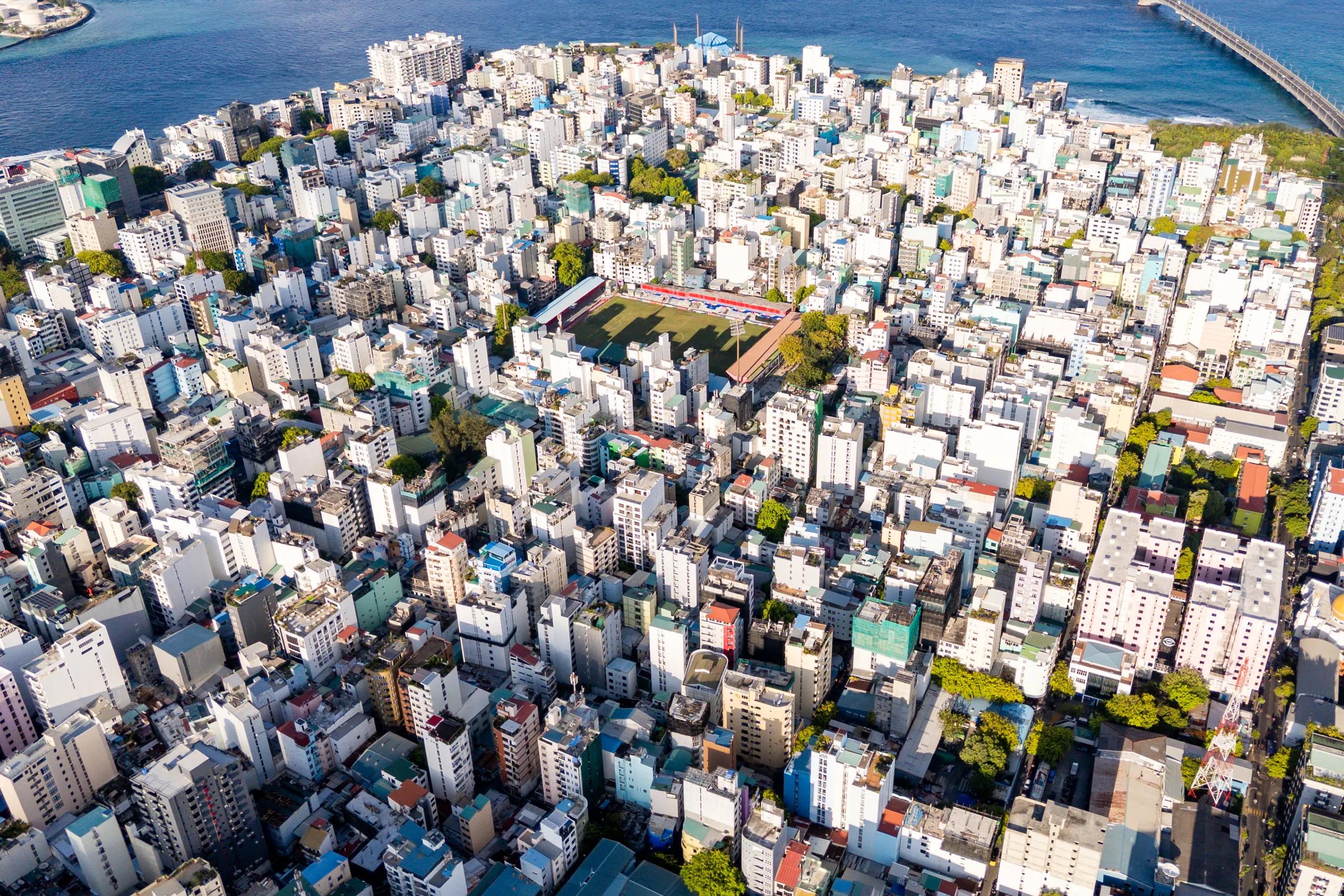 High drone view of Malé packed edge to edge with buildings, the Sinamalé Bridge at the top right