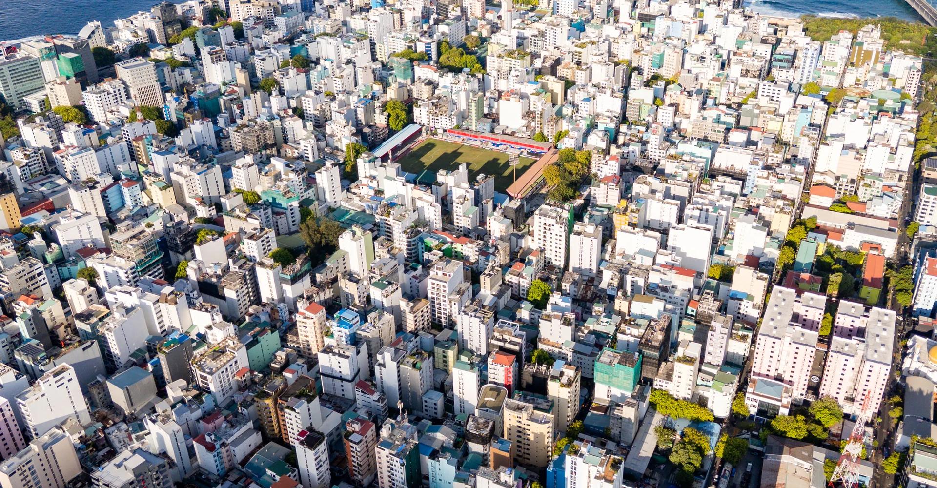 High drone view of Malé packed edge to edge with buildings, the Sinamalé Bridge at the top right