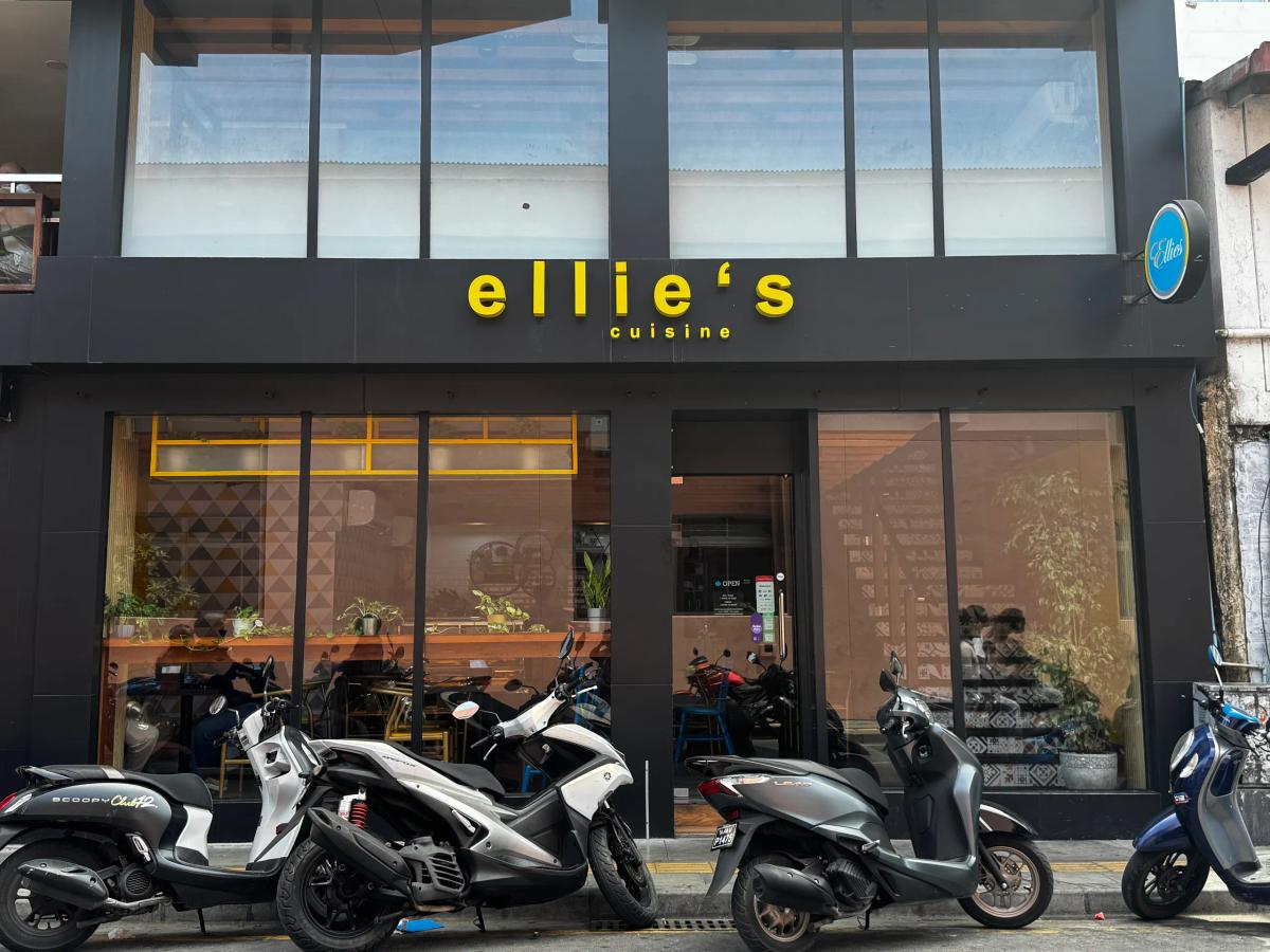Black storefront with yellow Ellie's Cuisine signage and parked scooters lined up out front