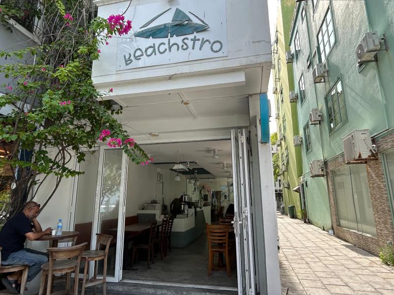 Beachstro's white corner storefront with its driftwood logo and folding glass doors open to the dining room
