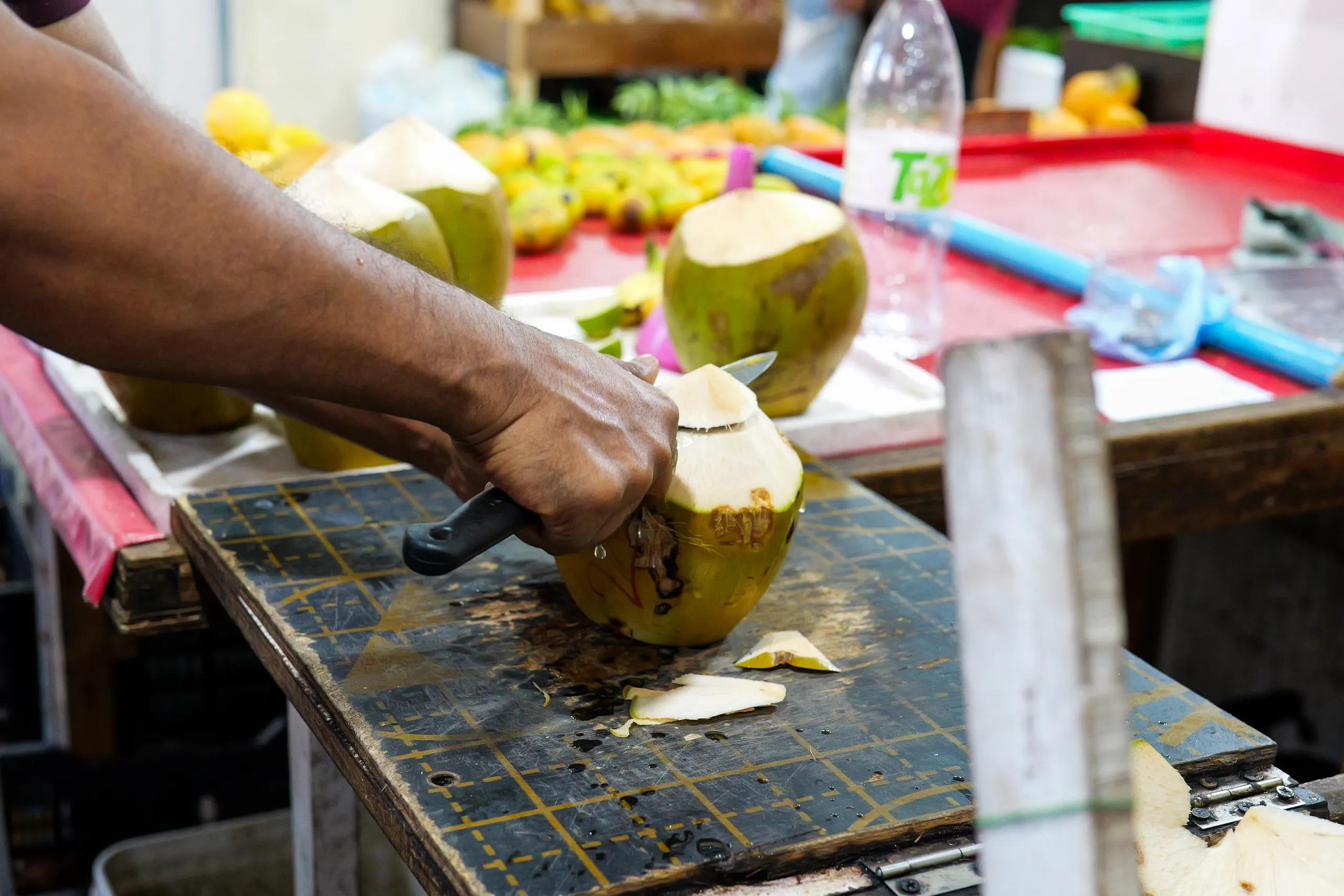 A vendor slicing open a fresh kurumba, a young coconut, at a market stall in Malé