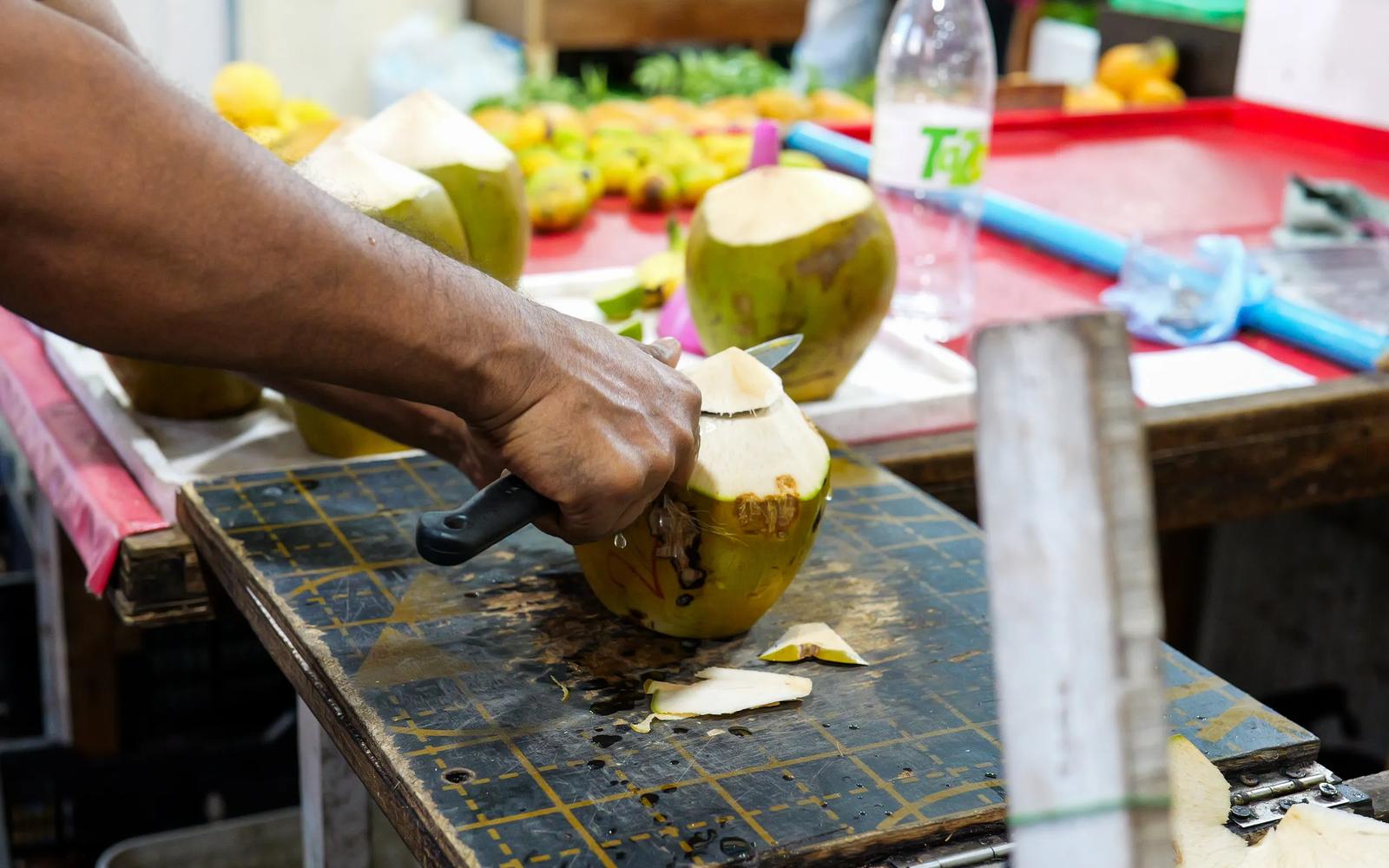 A vendor slicing open a fresh kurumba, a young coconut, at a market stall in Malé