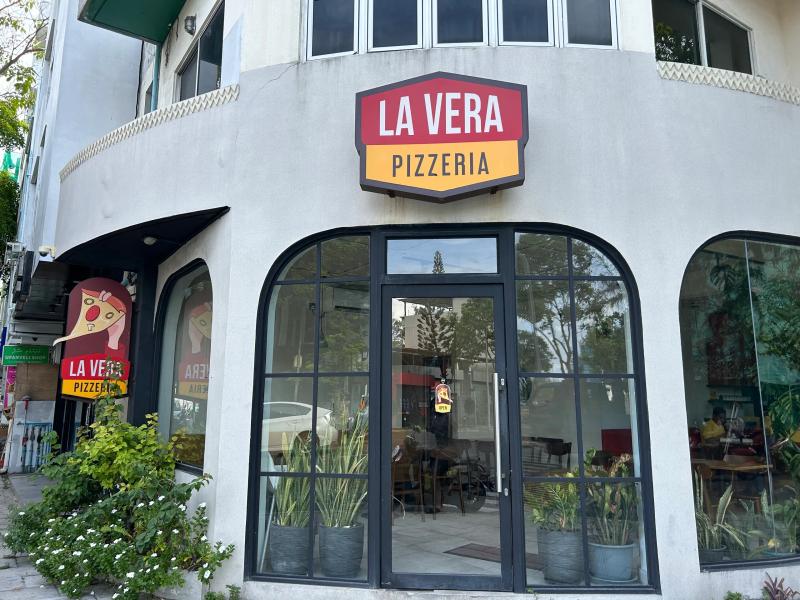 La Vera Pizzeria sign above the tall arched glass front of the Hulhumalé branch, with potted plants by the door