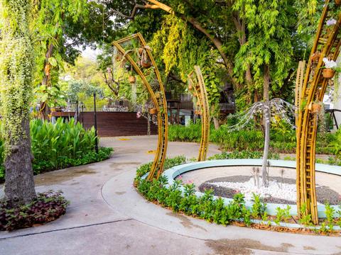 Circular fountain ringed by curved yellow arches and lush planting in Sultan Park