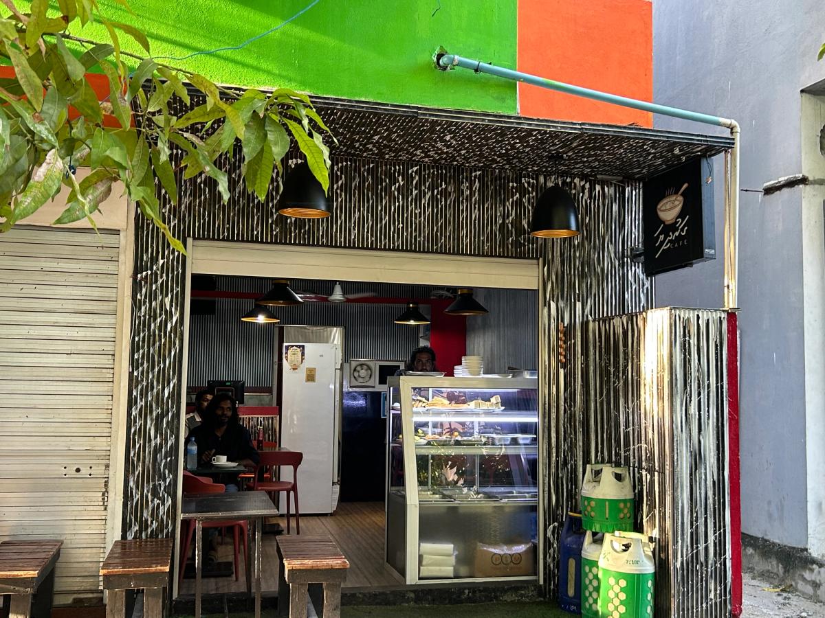 Open-fronted Garudhiya Cafe with a lit display case of food and diners seated inside