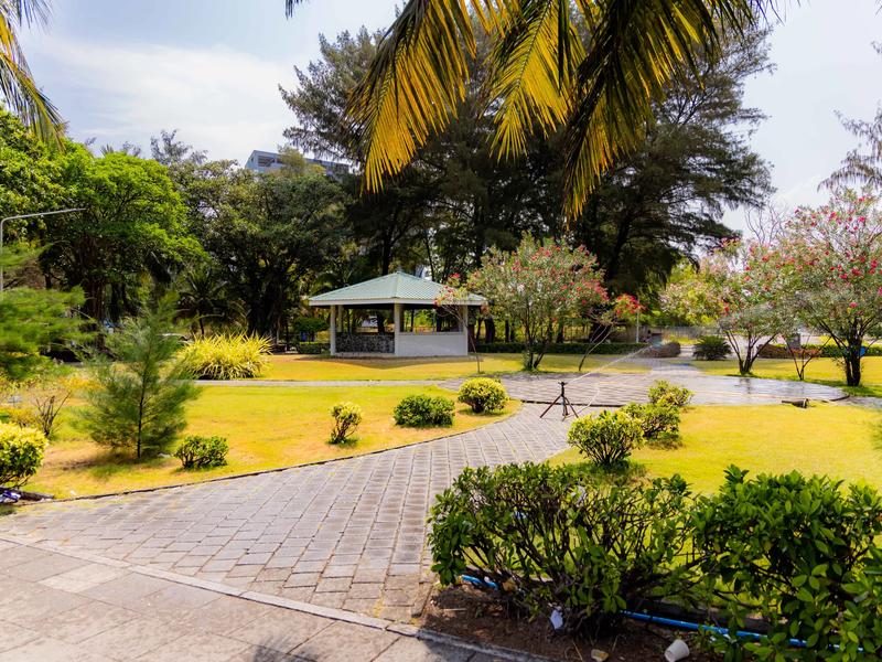 Green pavilion and paved paths through landscaped lawn with flowering shrubs at Hulhumalé Ferry Terminal Park