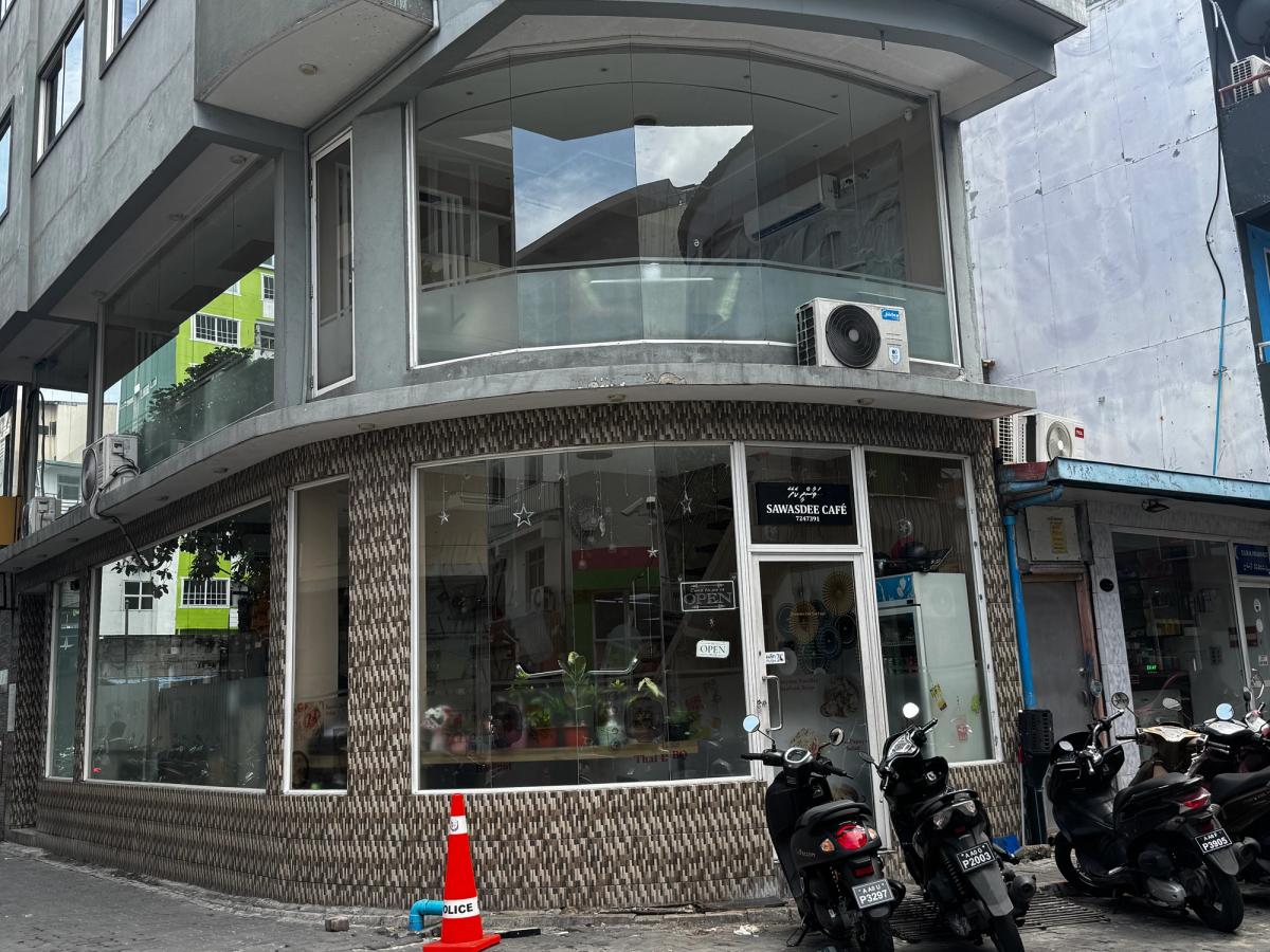 Sawasdee Cafe on a street corner with curved glass windows and an Open sign, motorbikes parked along the kerb