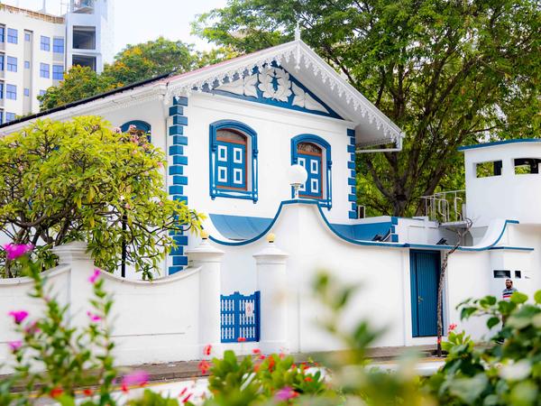 Ornate white building with blue trim and arched windows behind a wall at Muliaage in Malé