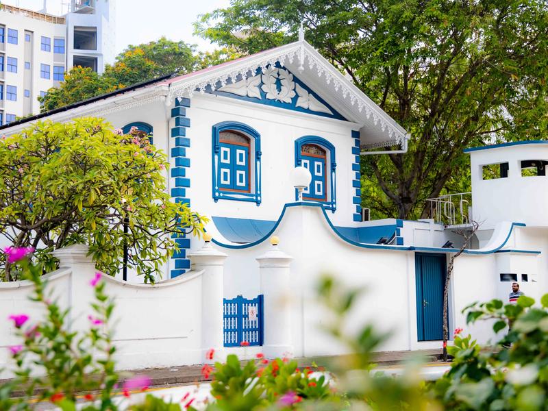 Ornate white building with blue trim and arched windows behind a wall at Muliaage in Malé