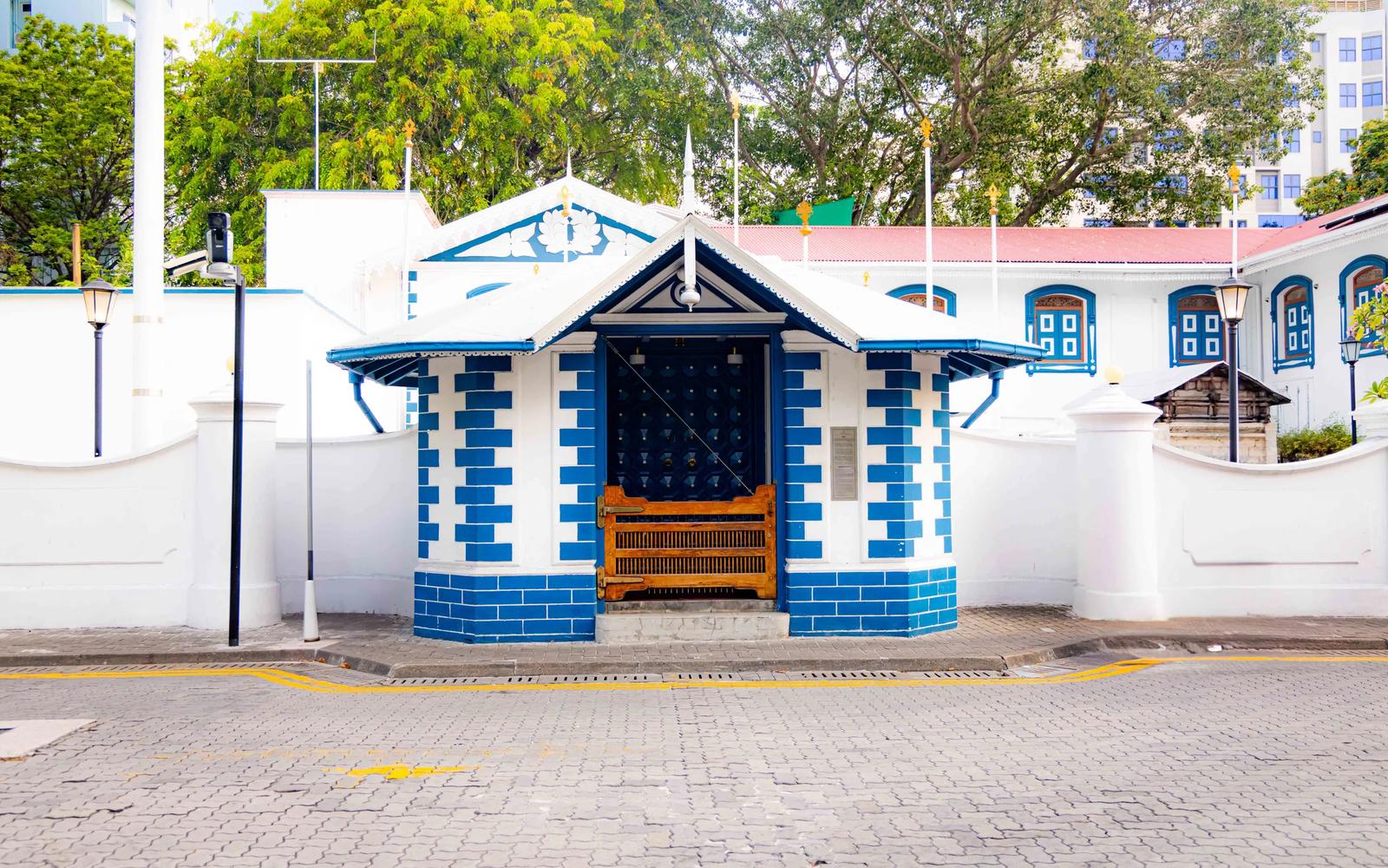 Blue-and-white tiled gatehouse with a studded dark door on a brick-paved street at Muliaage