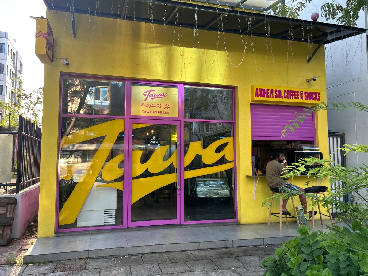 Bright yellow Tawa Express shopfront with large script logo and a customer at the pink takeaway window