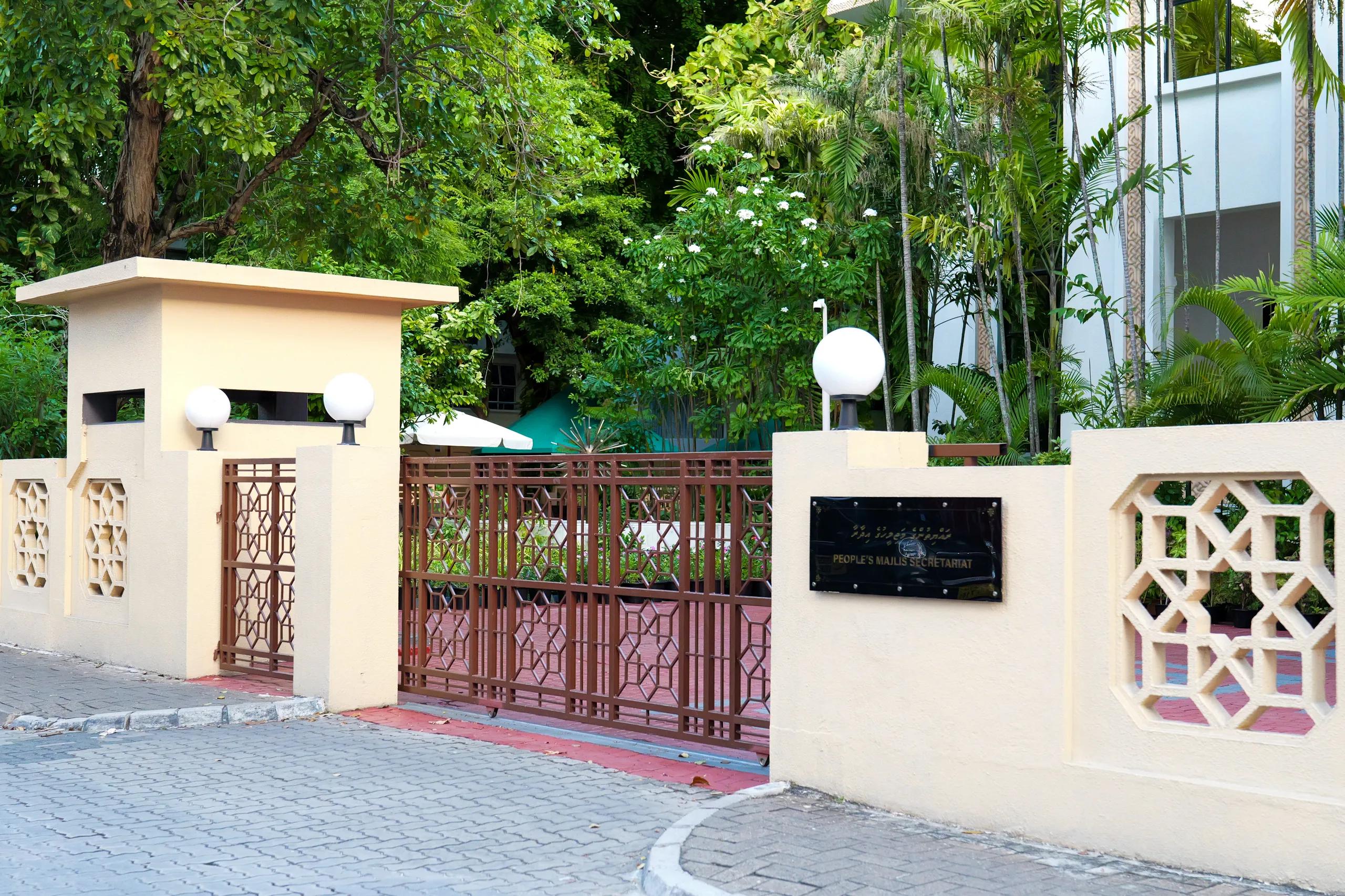 Entrance of the People's Majlis in Malé, with a geometric metal gate, patterned cream walls and the secretariat plaque