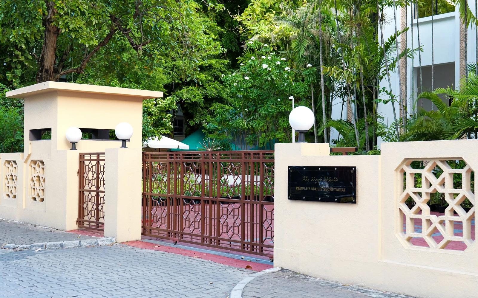 Entrance of the People's Majlis in Malé, with a geometric metal gate, patterned cream walls and the secretariat plaque