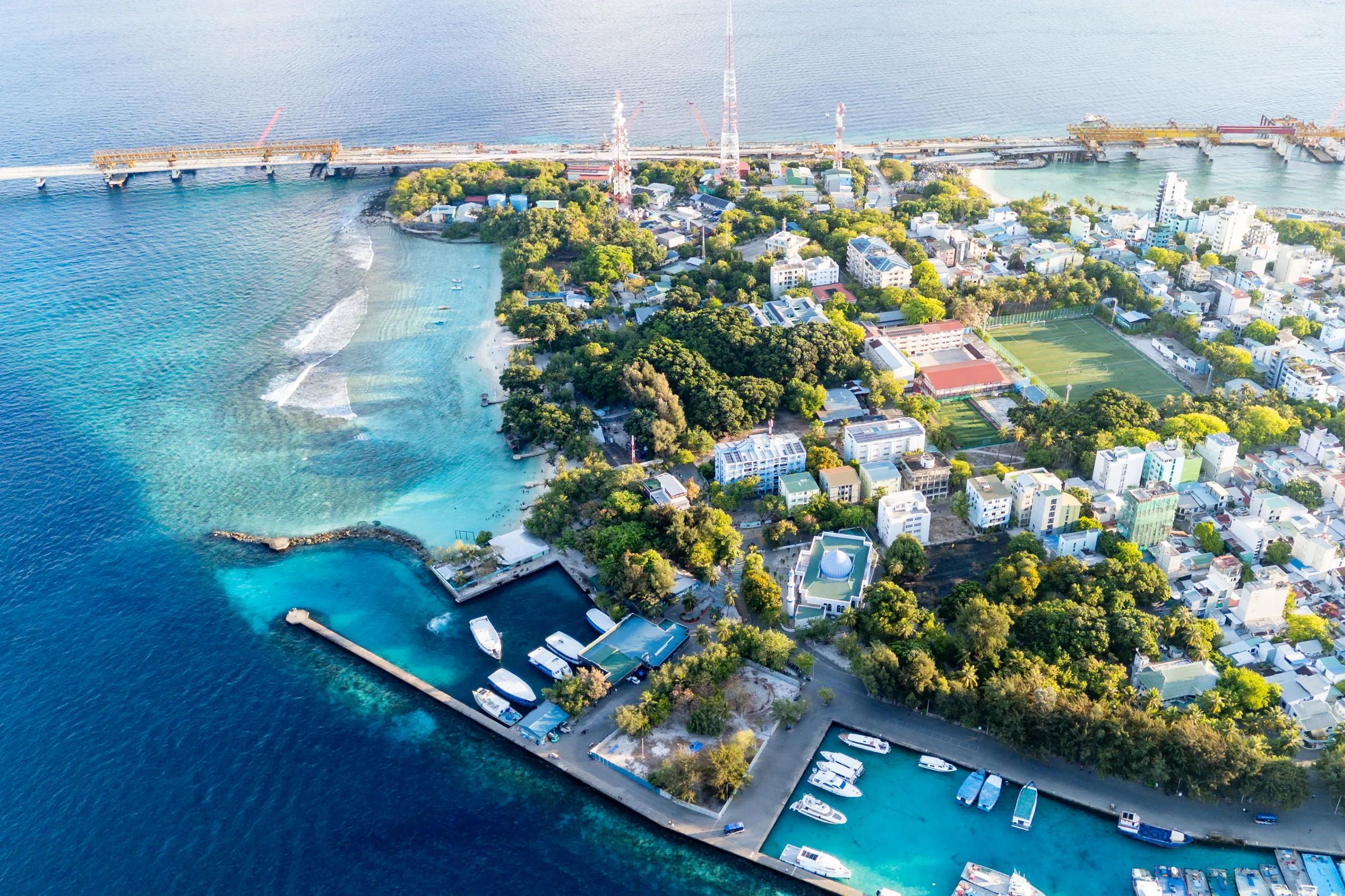 Aerial view of Vilimalé, a green low-rise island with a harbour and moored boats