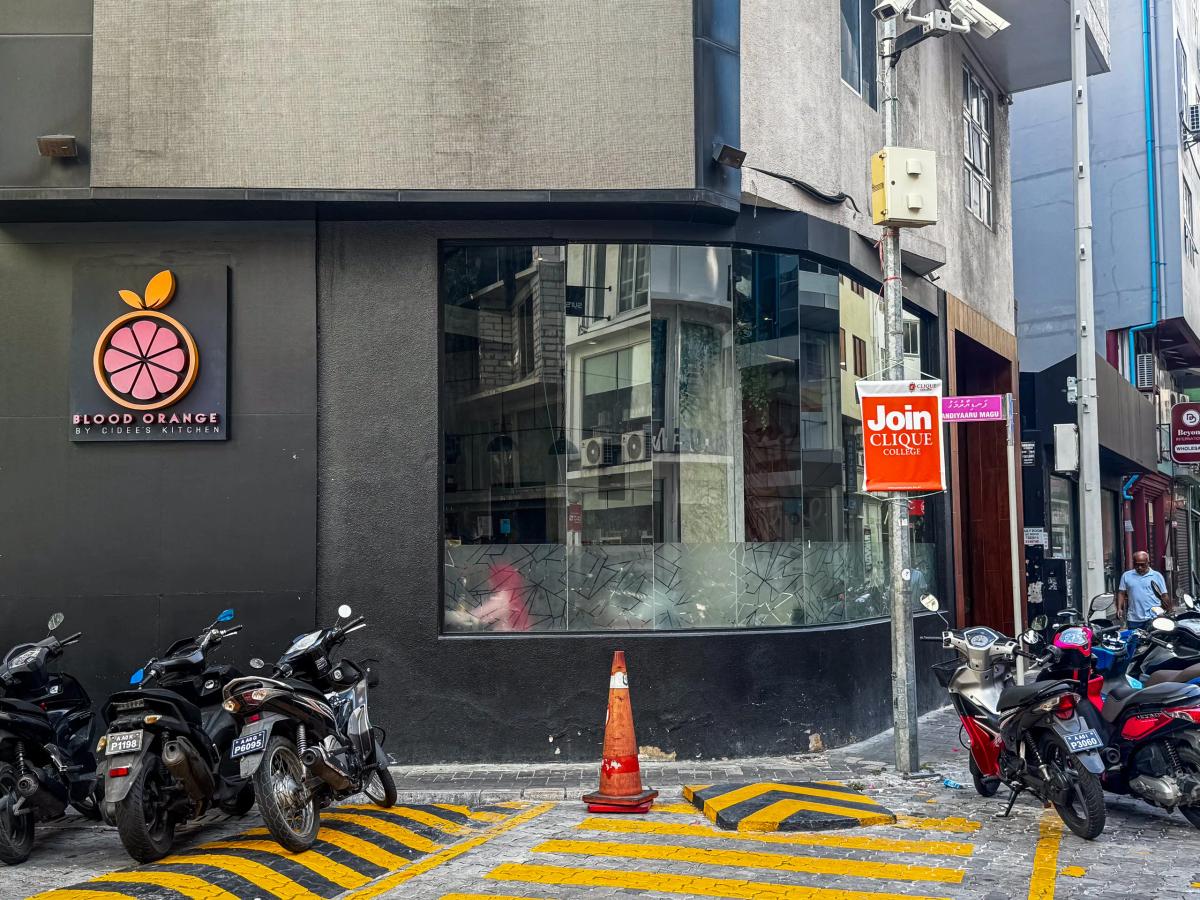Blood Orange by Cidee's Kitchen on a black corner building with a pink blood-orange logo and a curved glass window