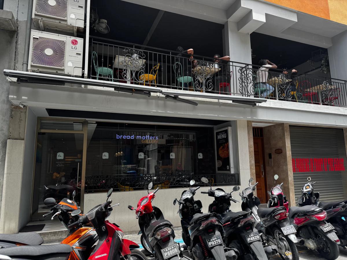 bread matters Gallery with a balcony of colourful bistro chairs above and motorbikes parked out front