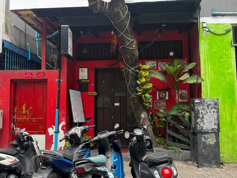 Red timber storefront of Som Tam Thai with menu board, framed food photos and parked scooters out front