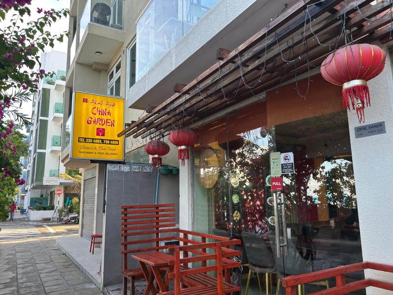 China Garden's yellow sign and red lanterns over the glass entrance of the Hulhumalé branch, with red benches on the pavement