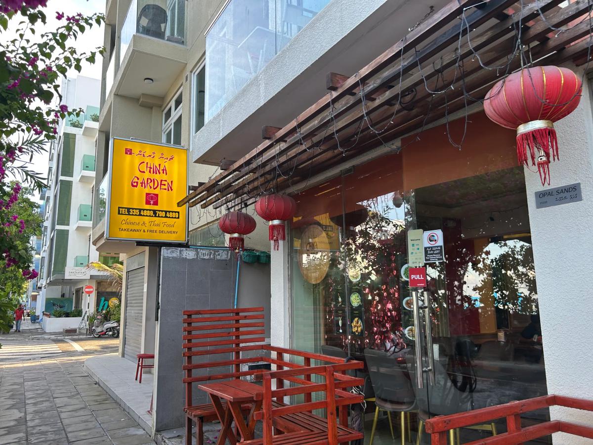 China Garden's yellow sign and red lanterns over the glass entrance of the Hulhumalé branch, with red benches on the pavement