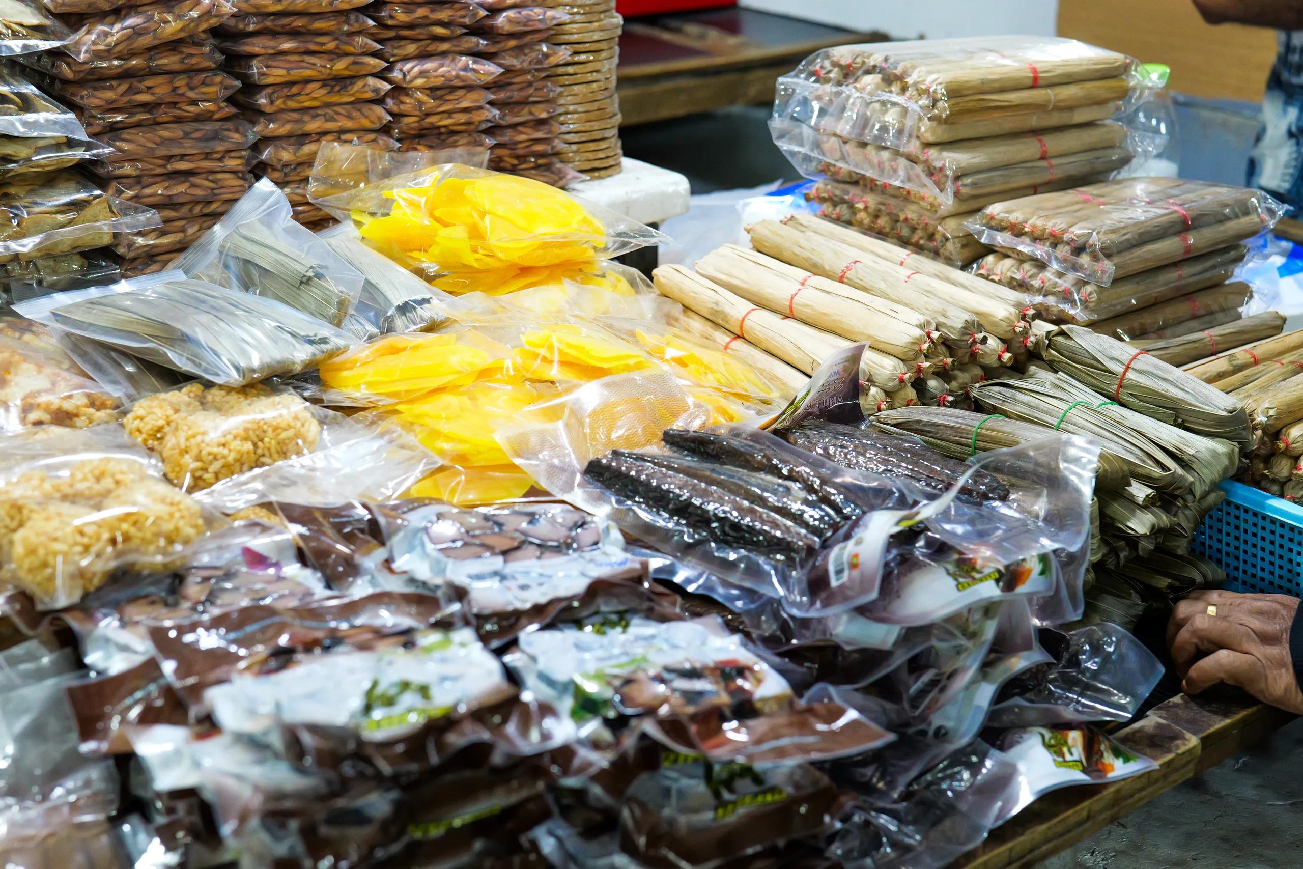 Vacuum-packed dried fish, bondi rolls wrapped in palm leaf and other local goods stacked on a Malé market stall