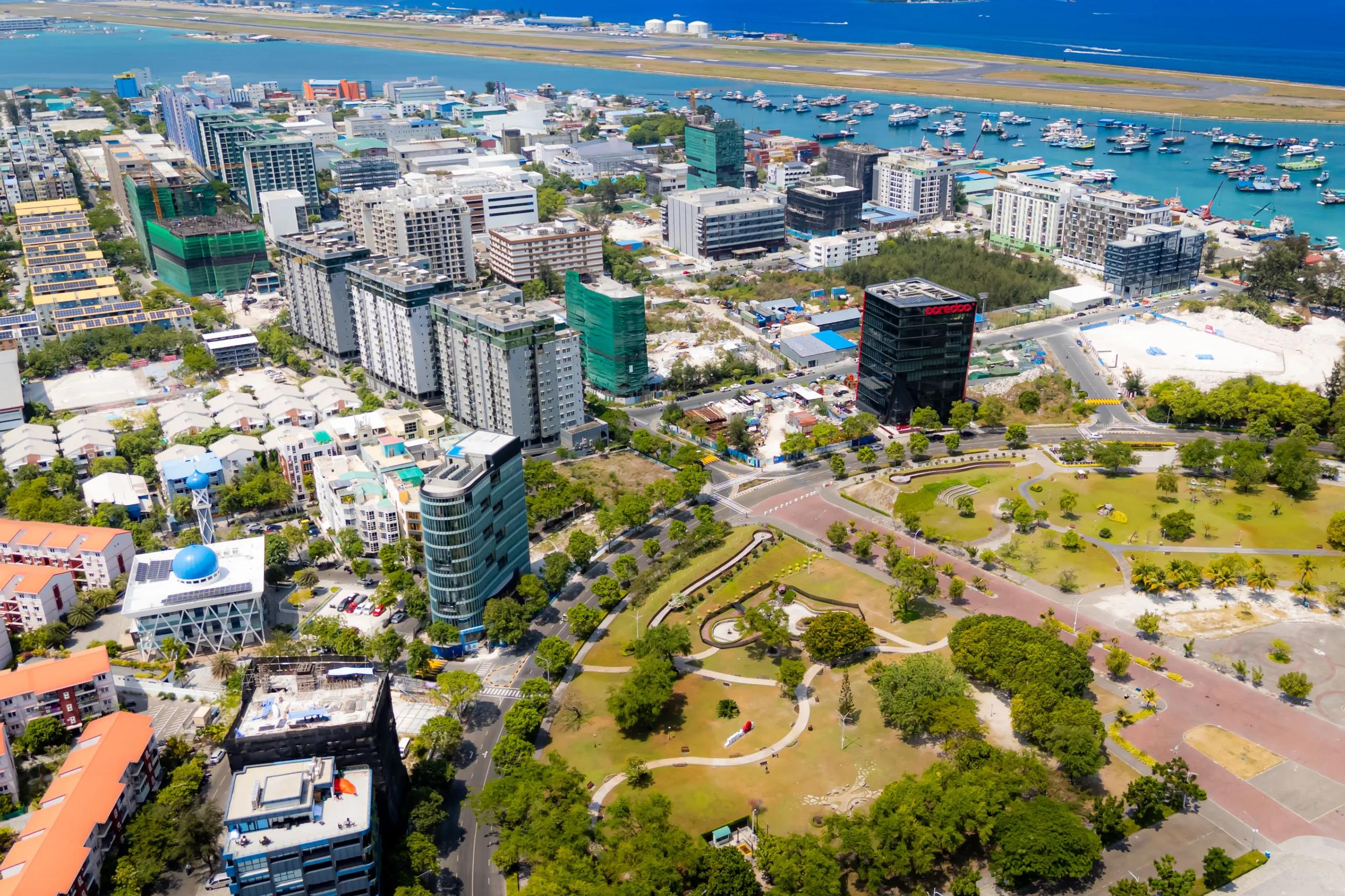Aerial view over Hulhumalé rooftops and parkland with boats offshore