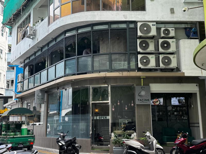Corner building housing Tajine Arabic Restaurant, with curved upstairs windows and an Open sign on the glass door