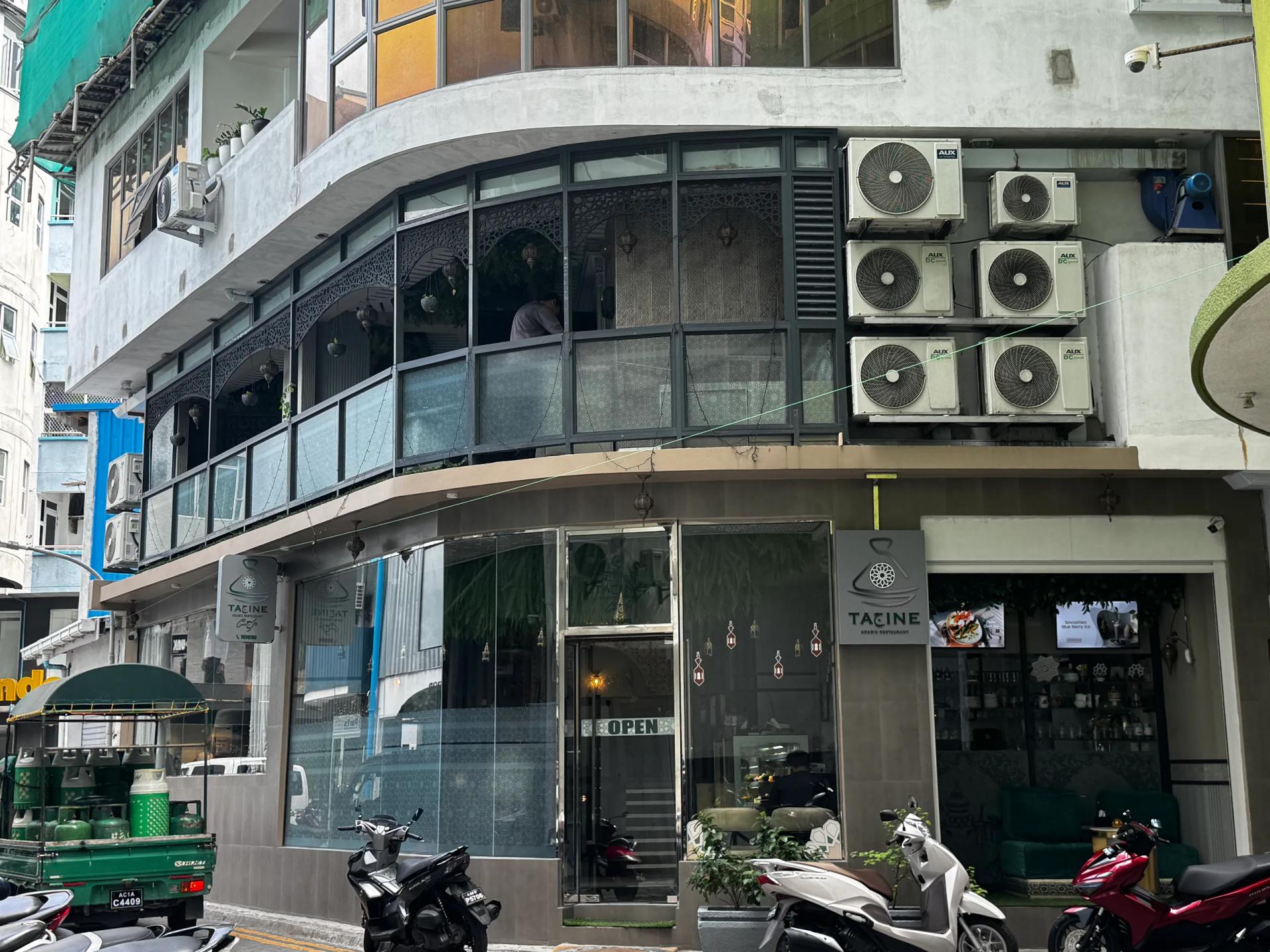 Corner building housing Tajine Arabic Restaurant, with curved upstairs windows and an Open sign on the glass door