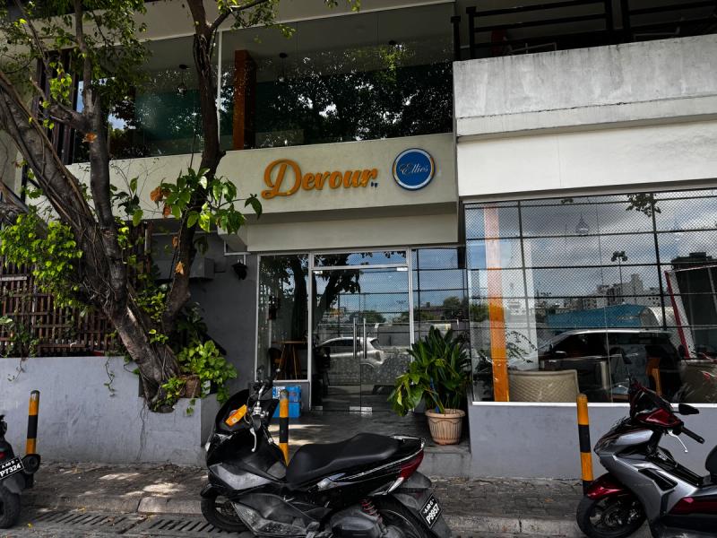 Devour by Ellies' script sign above a glass-walled front, shaded by a large tree