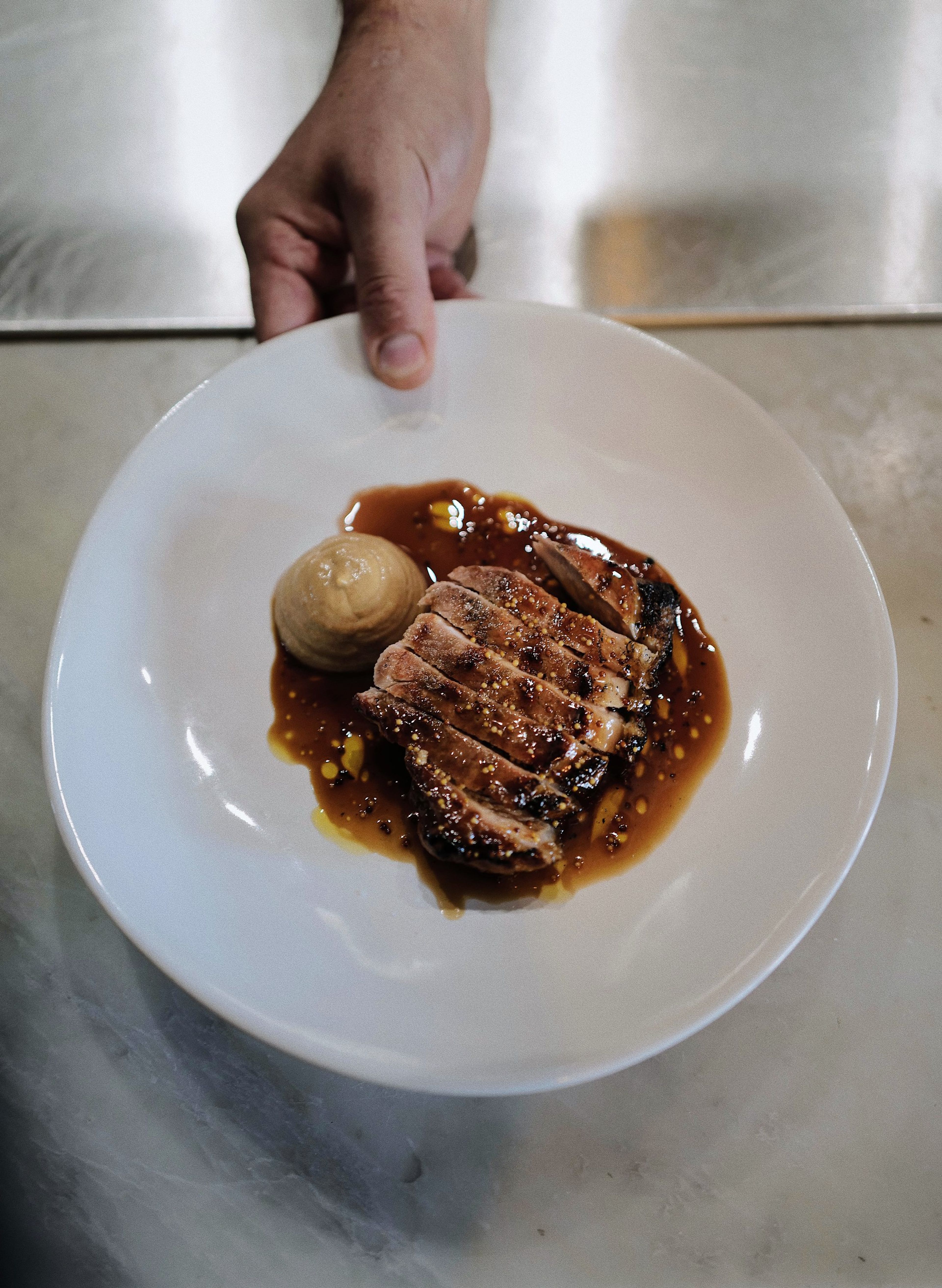 Iberico pork chop with smoked apple purée, held out on a white plate