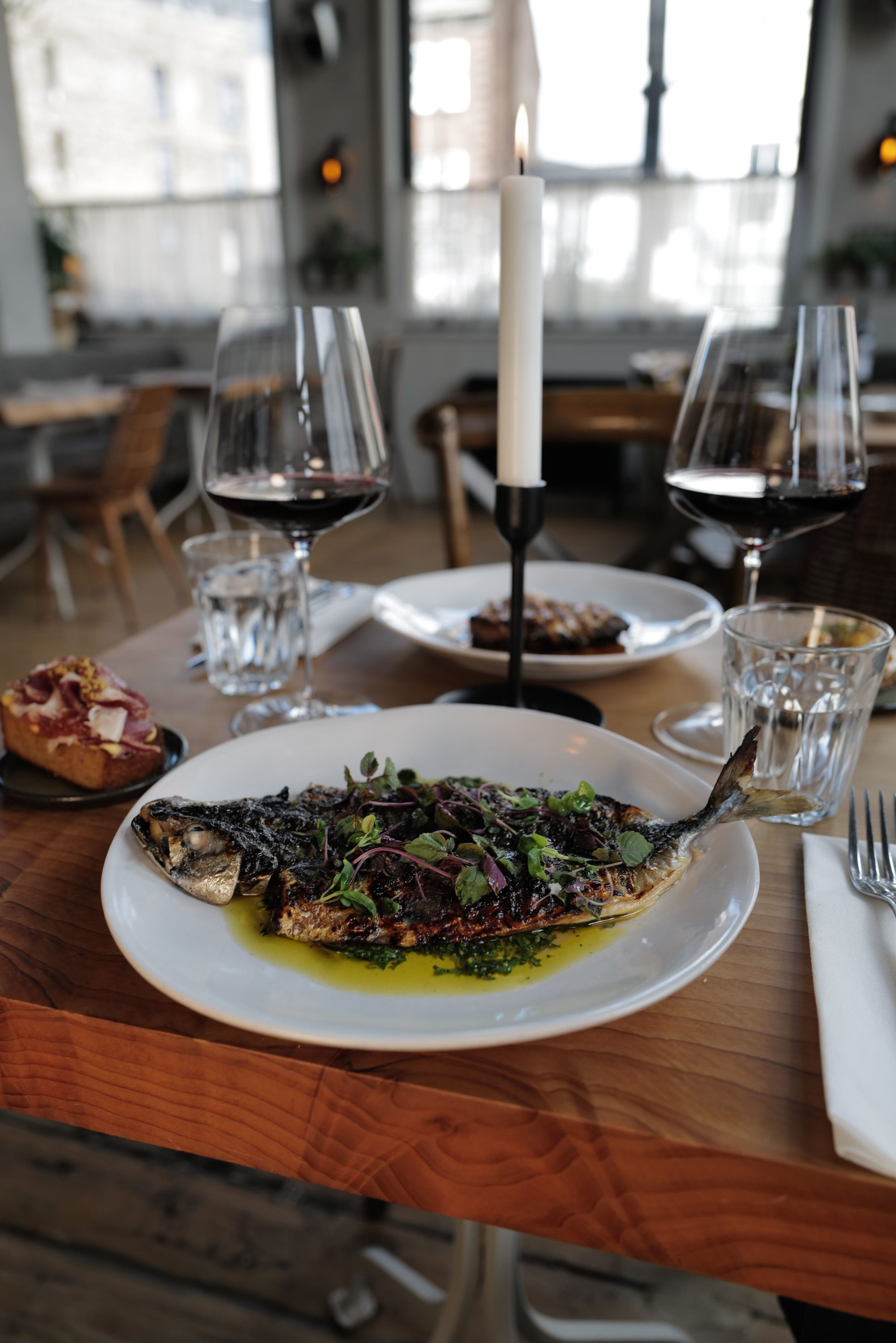 Grilled mackerel with glasses of red wine and candles in the dining room