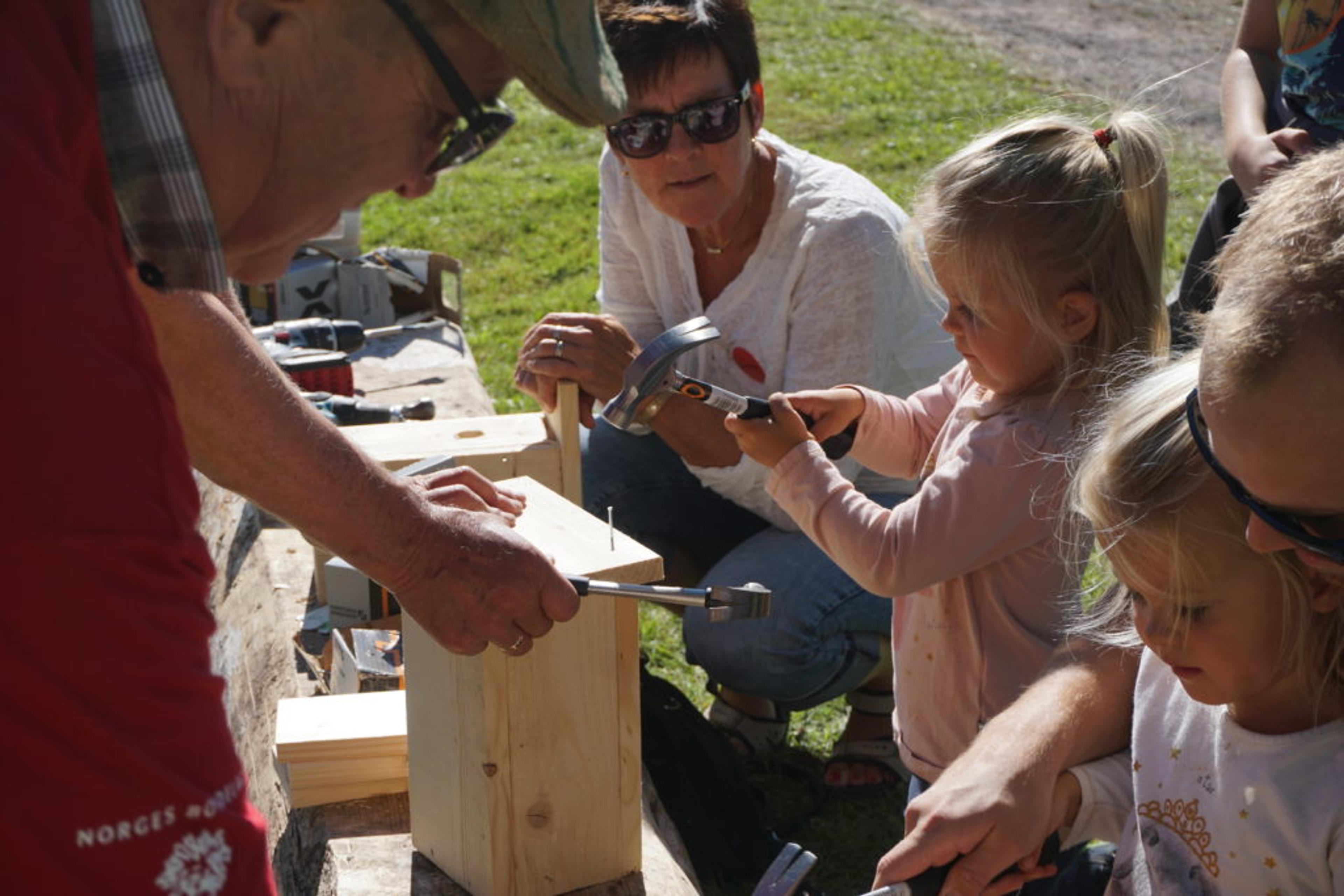 Otilie Ommedal snekrer fuglekasse ved siden av søsteren Olivia Ommedal og farmor