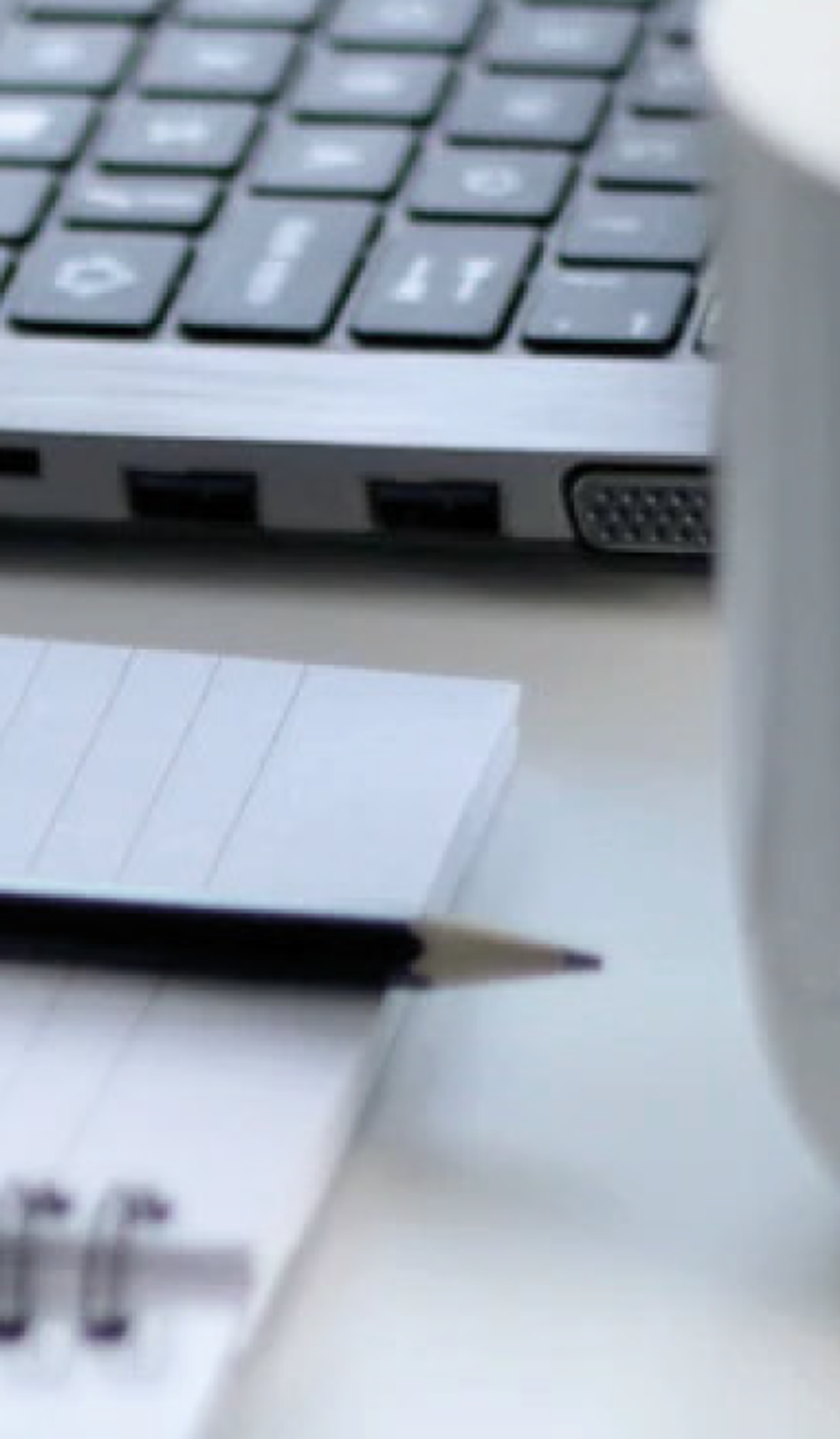 Imagem de um computador, com lápis e caderno para anotações ao lado.