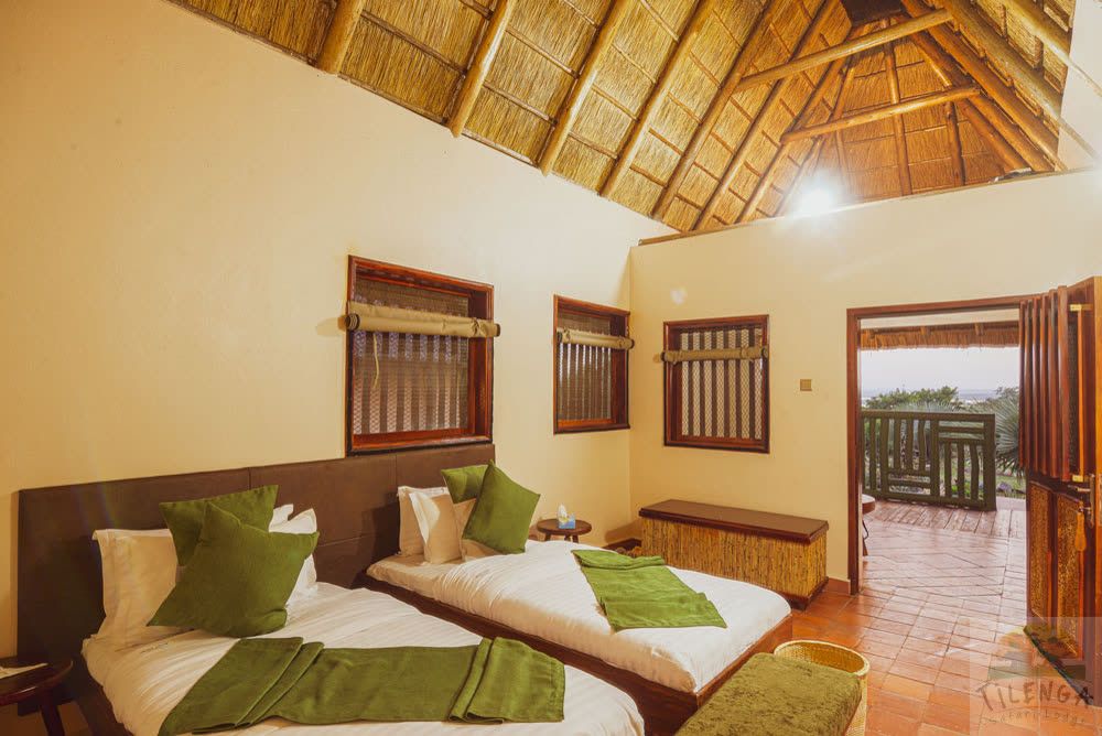 Twin beds in a cottage under an open thatched roof