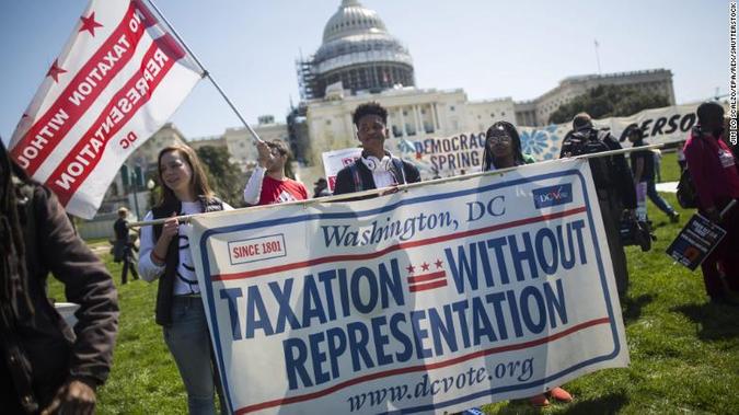 People carrying a banner that says 'Taxation Without Representation'.