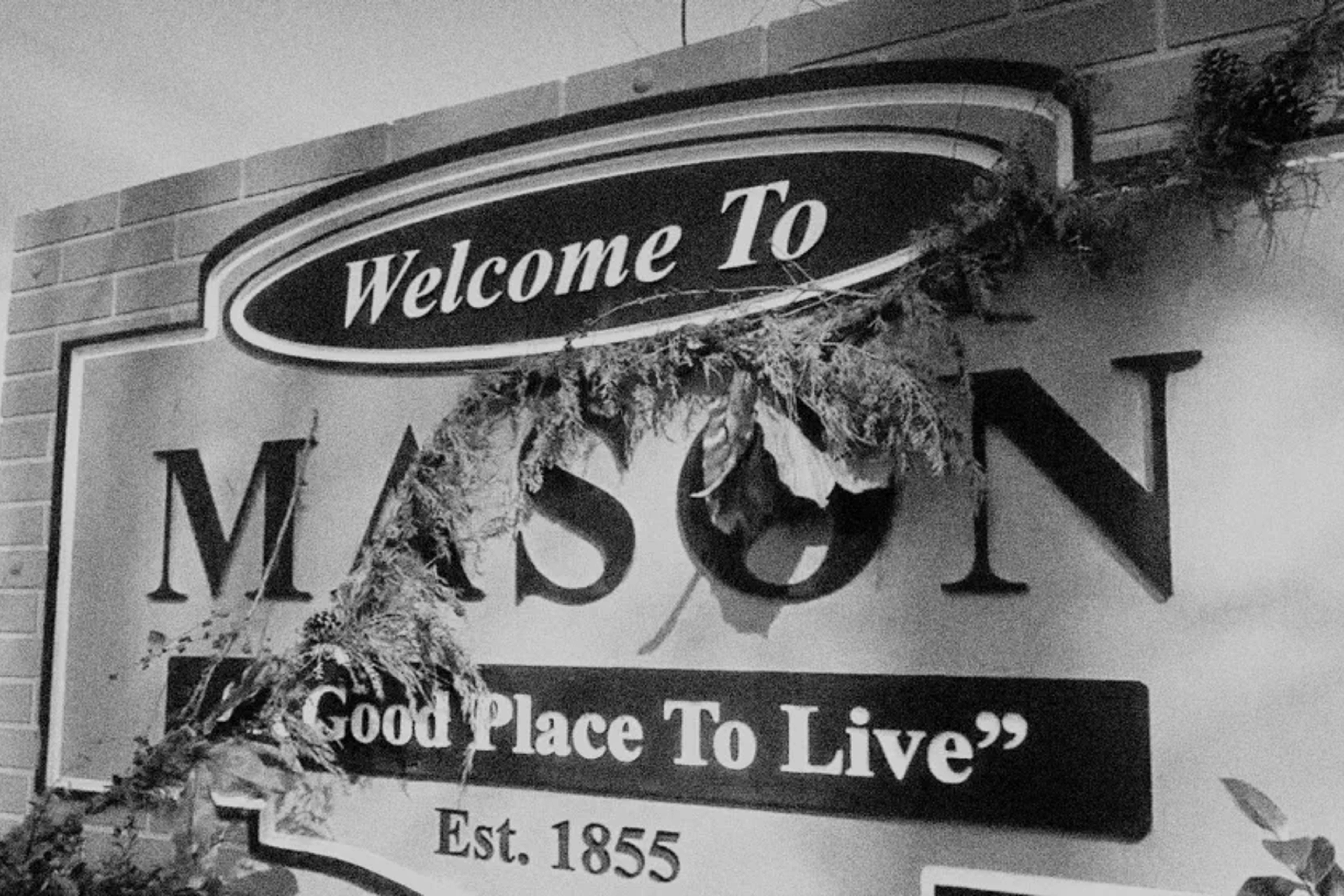 Black and white photograph of a sign that reads, "Welcome to Mason, a good place to live, established 1955"