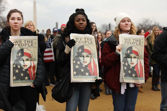 Three women holding up "we the people" posters