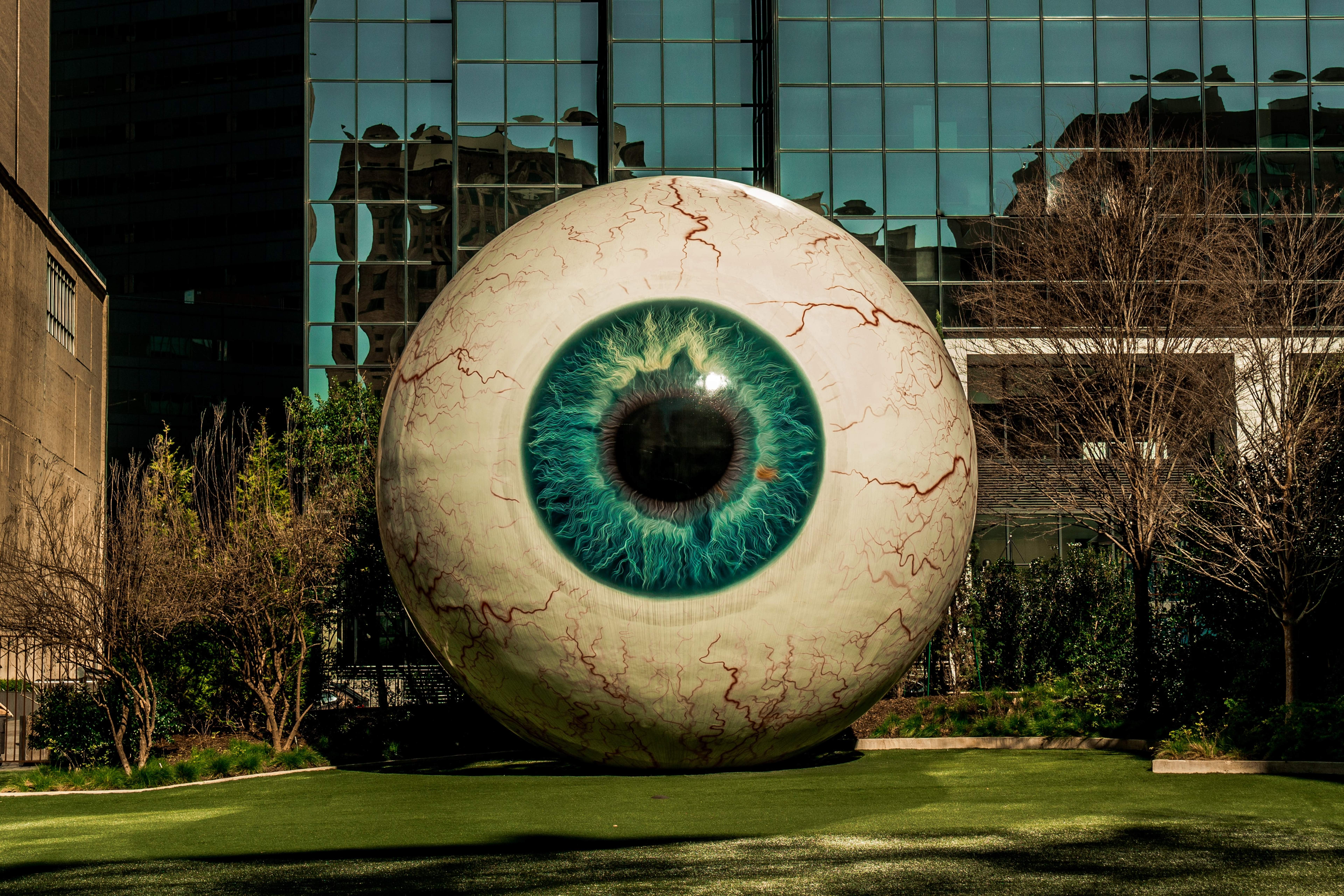 Sculpture of a giant bloodshot eye on the lawn in front of a glass office building