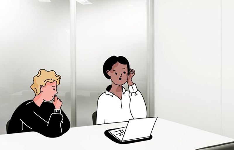 En voksen og en ungdom sitter ved et bord. Den voksne sitter foran en pc og ungdommen ser på den voksne.
