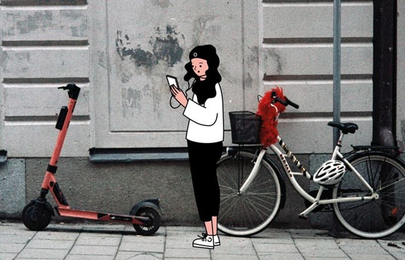 En jente står foran en el-sparkesykkel og en annen sykkel med kurv. Hun ser på mobilen sin og hører på musikk