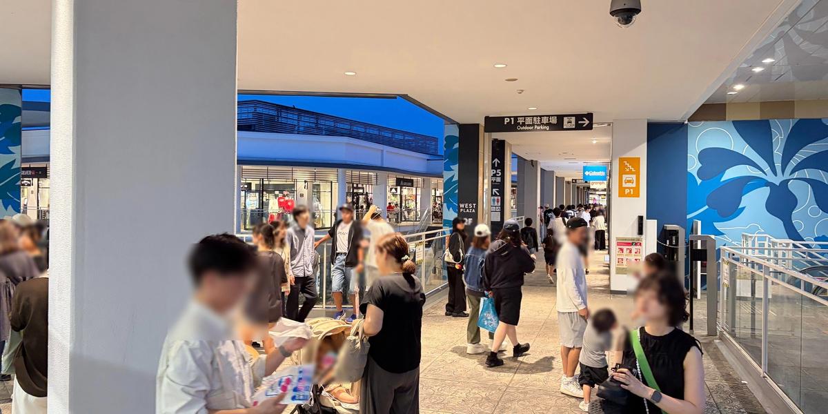 夕方のアウトレットの屋根のある通路。多くの人が行き交っている