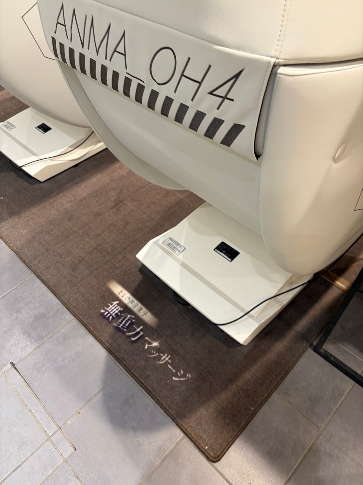 マッサージチェアの側面に入った ANMA OH4 のロゴ。足元のマットに「無重力マッサージ」の文字がある