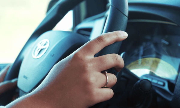 A hand holding a steering wheel