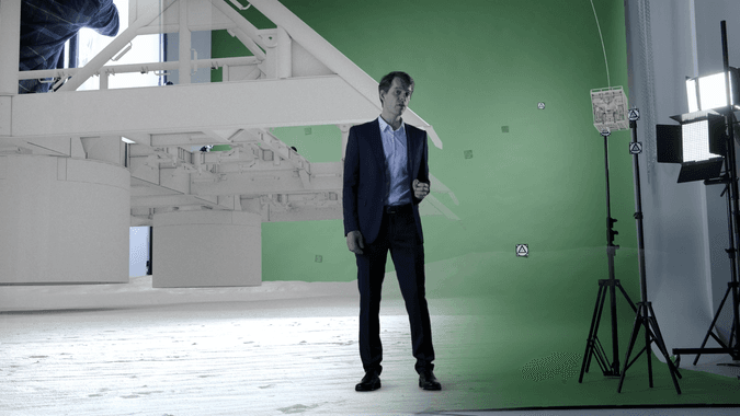 A man in front of a greenscreen with half a subsea environment
