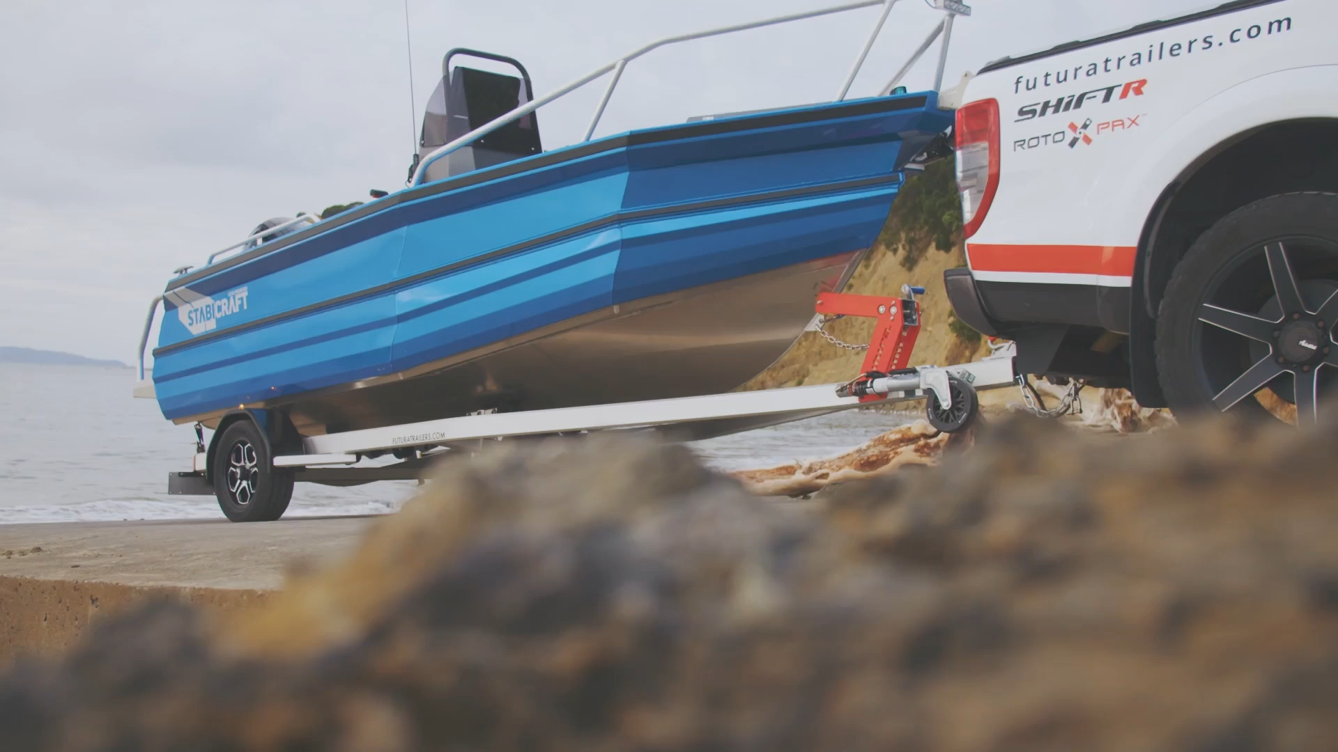 Futura S475 QDK Boat Trailer at the beach, near water, with rocks in the foreground