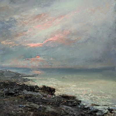 A few pink clouds lingering as the sun sets over a rocky shore.