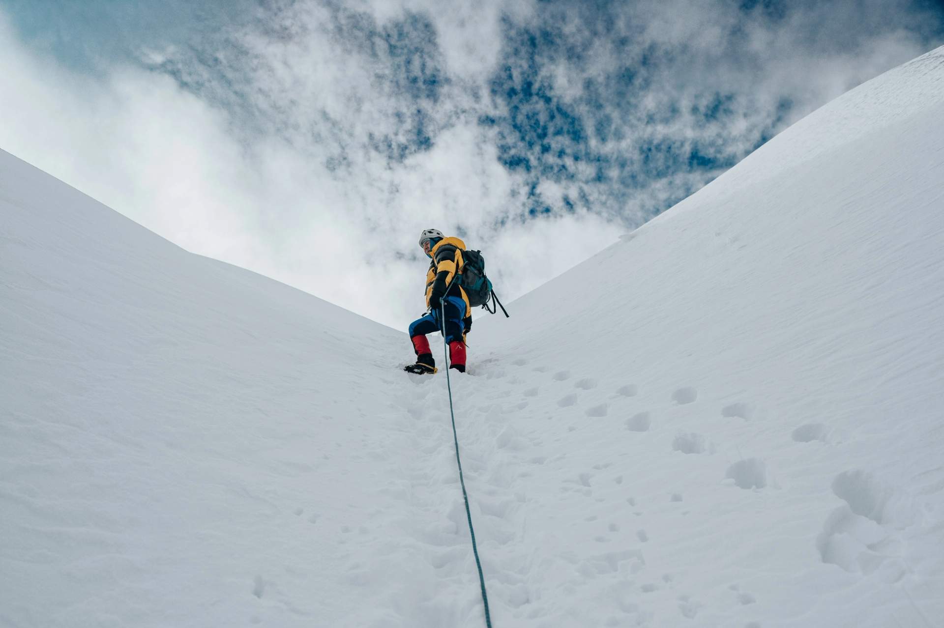 Alpiniste encordé progressant sur une arête enneigée