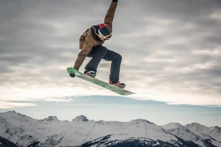 A snowboarder mid-air above snowy mountains