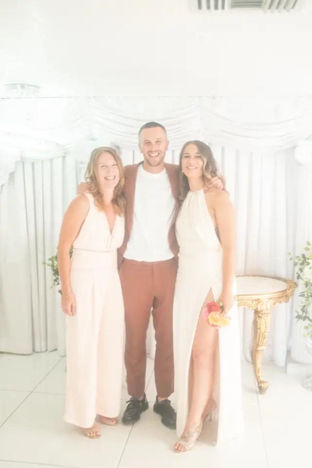Three friends smiling together in a bright white room