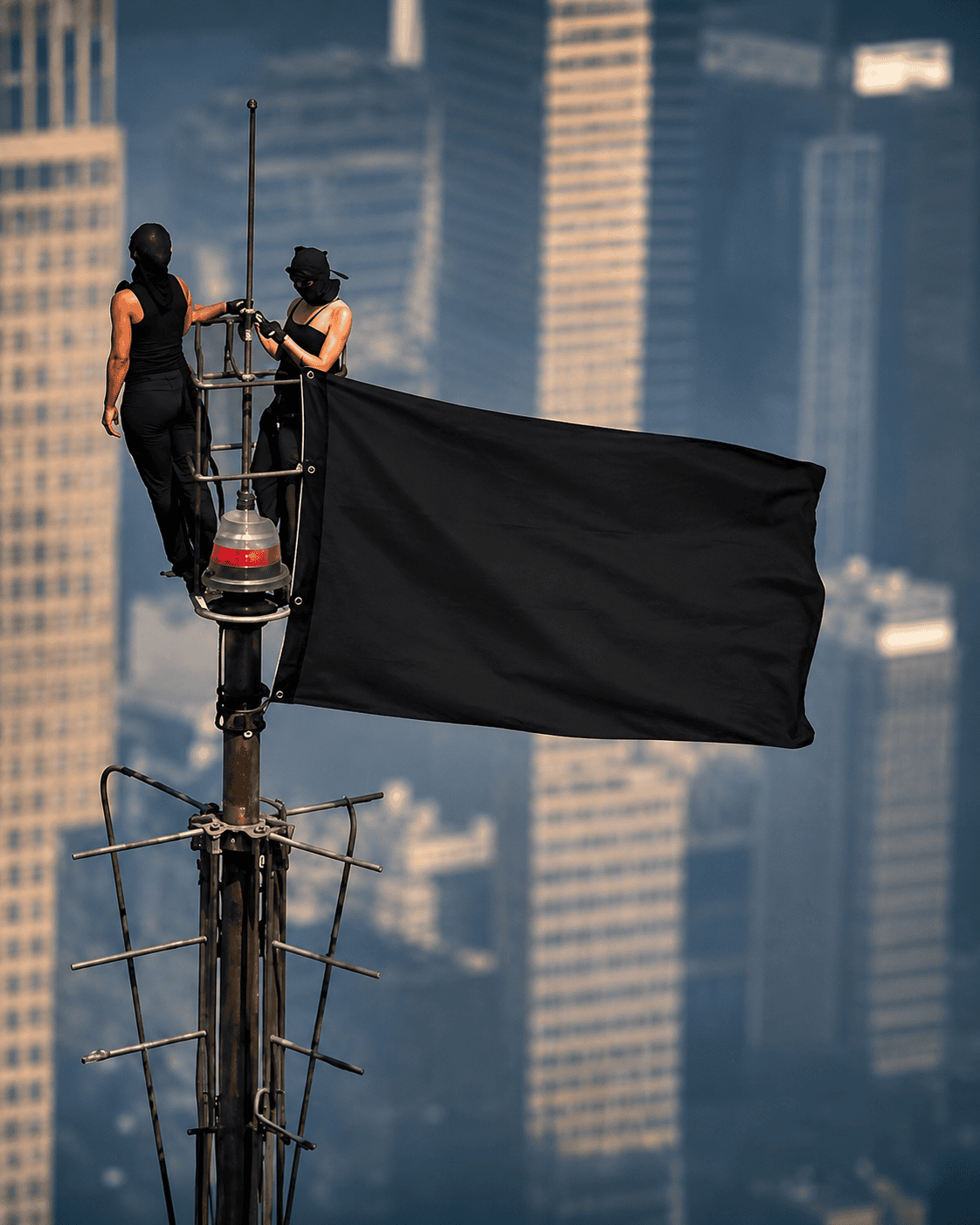 Tight 4:5 portrait crop of the masked pair and the large black flag, blurred skyscrapers behind