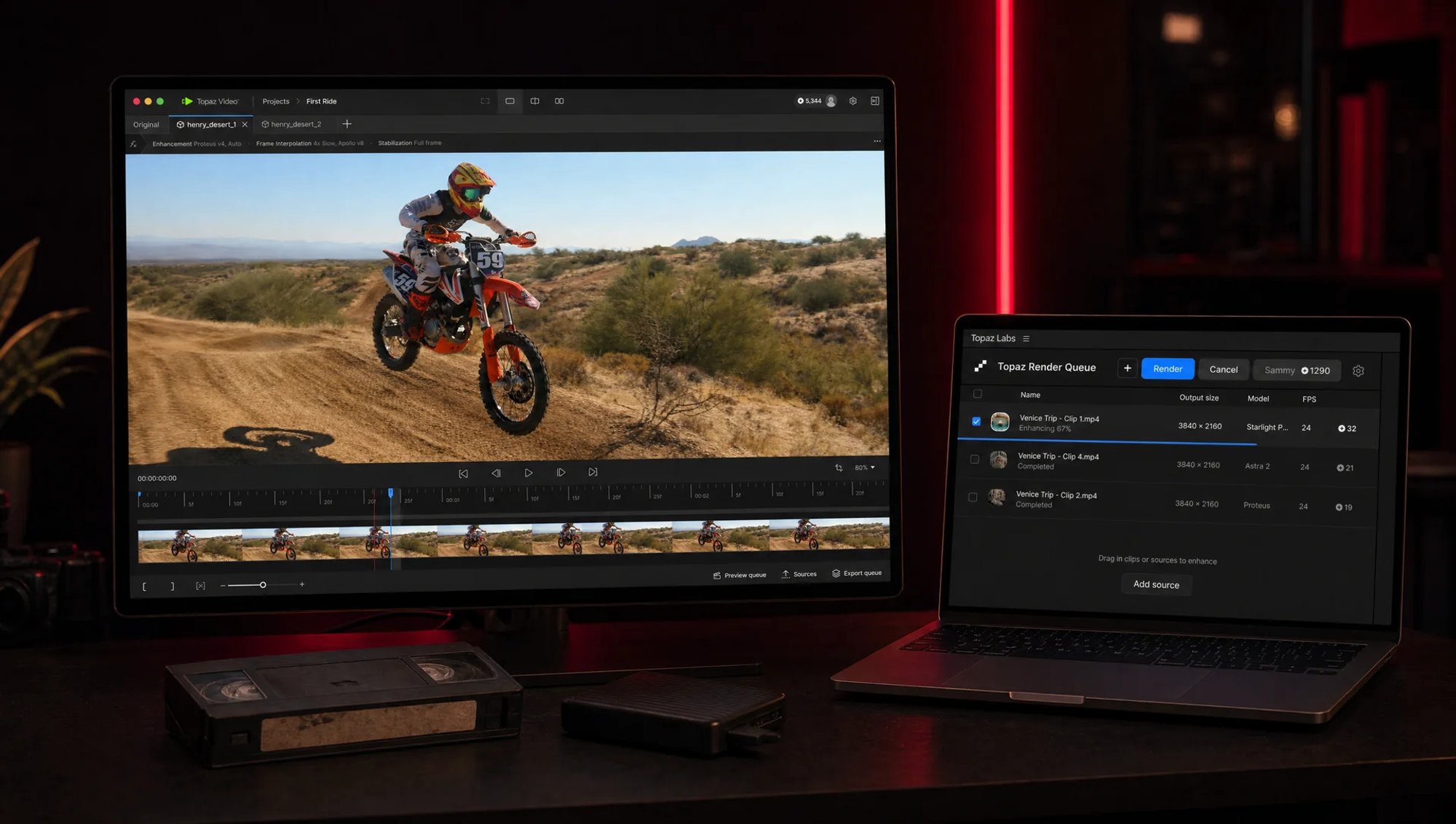Station de montage sombre éclairée en rouge : un écran affiche Topaz Video avec un plan de motocross, un portable montre la file de rendu Topaz, une cassette VHS posée devant